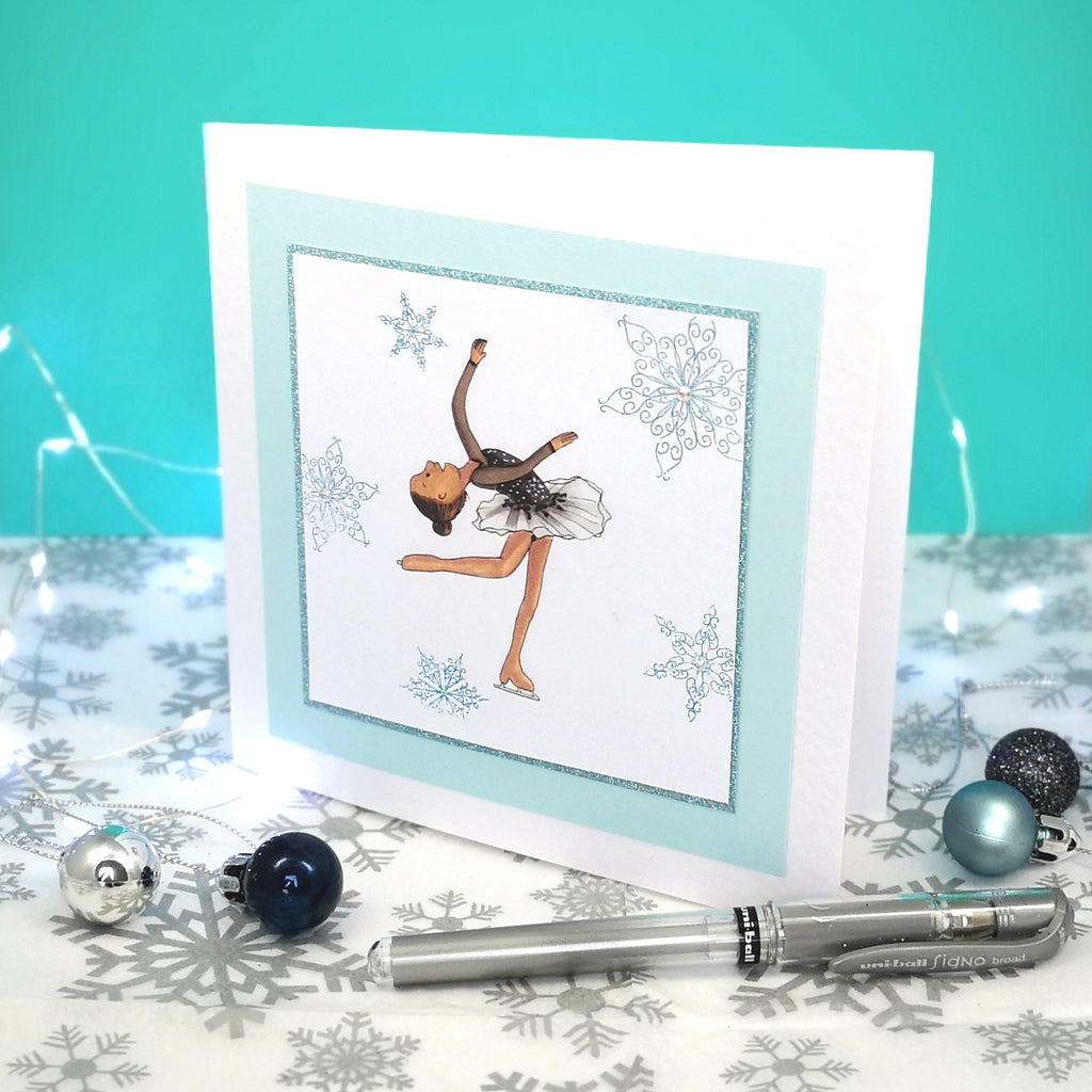 6 x 6 inch greeting card with image of a figure skater in a black dress, surrounded by blue foiled ornate snowflakes