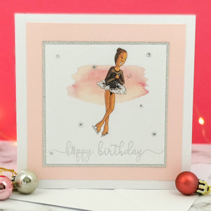 6 x 6 inch birthday card with image of a figure skater mid-flight, wearing a black dress. Pink watercolour brush stroke behind the figure skater illustration, with a silver foiled happy birthday script greeting and surrounded by clear/silver rhinestone gems