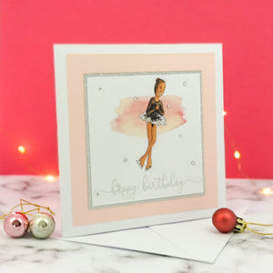 6 x 6 inch birthday card with image of a figure skater mid-flight, wearing a black dress. Pink watercolour brush stroke behind the figure skater illustration, with a silver foiled happy birthday script greeting and surrounded by clear/silver rhinestone gems